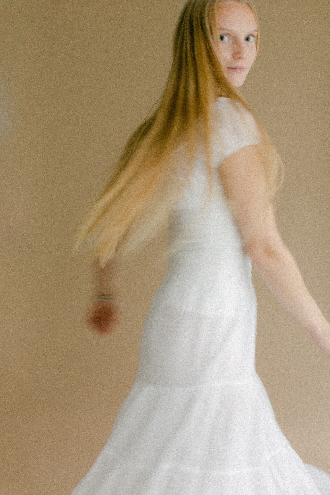 A woman in a white dress turns in motion, looking back over her shoulder.